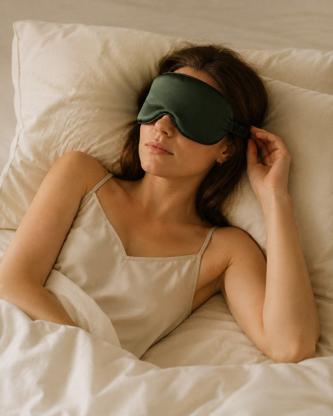 Woman wearing a Forest Whisper silk sleep mask while resting on a pillow